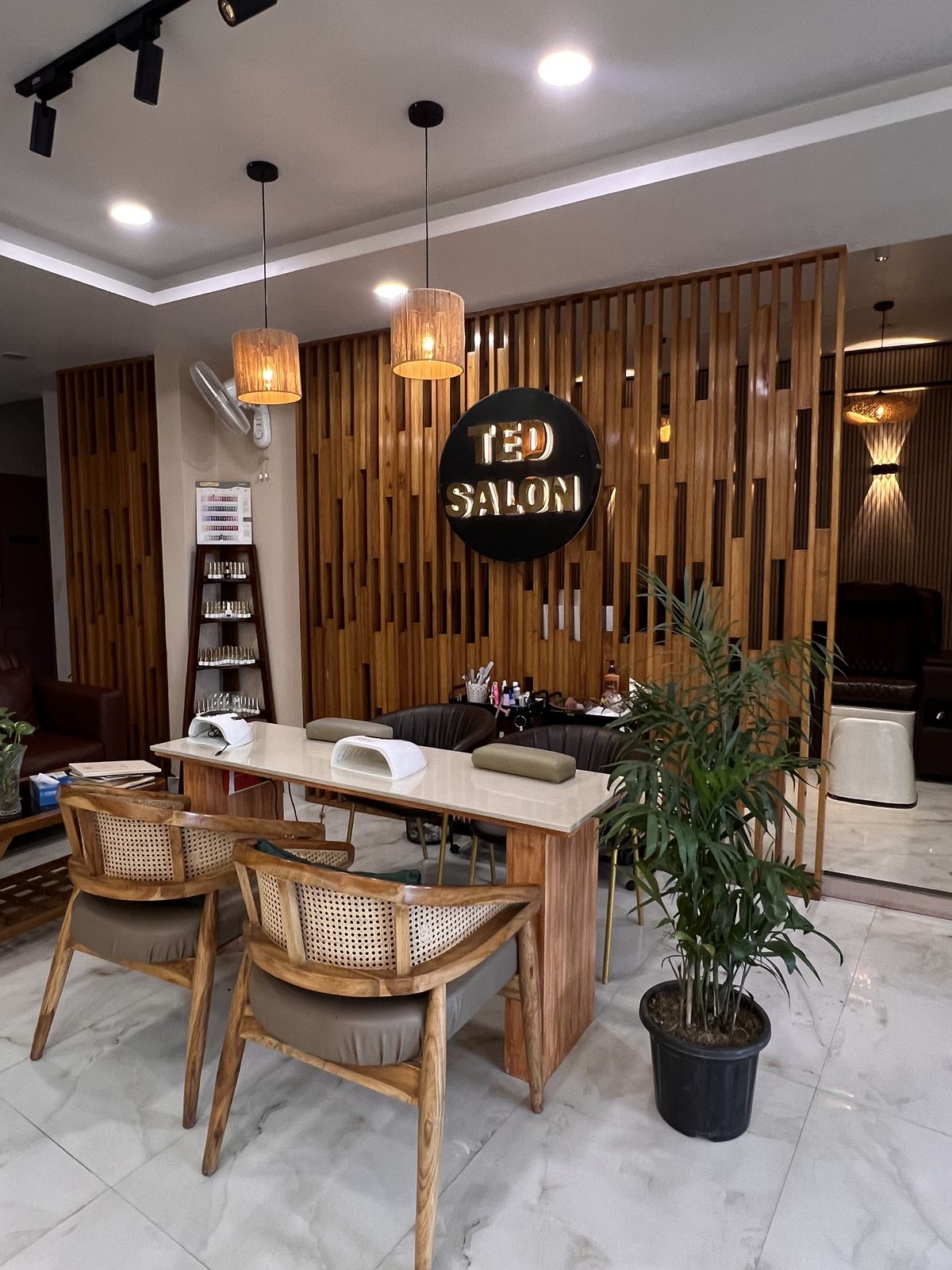 Ted Salon reception: the gold TED SALON sign over wood slats, a nail table and rattan chairs.