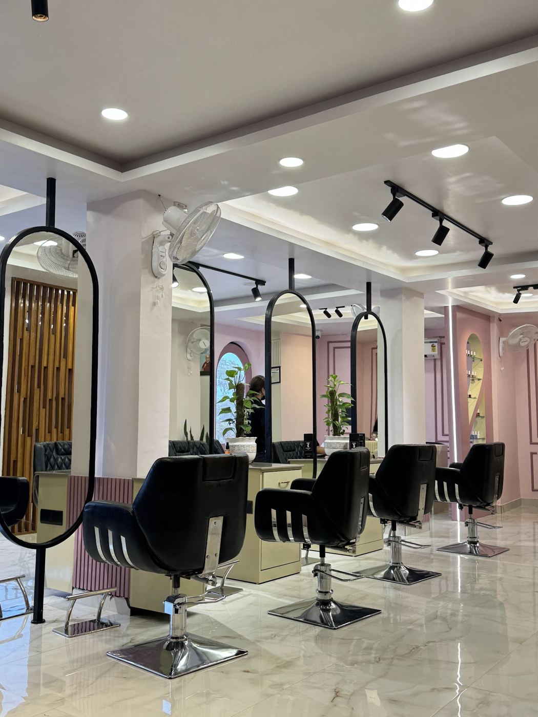 The main salon floor: black styling chairs, tall oval mirrors and track lighting.