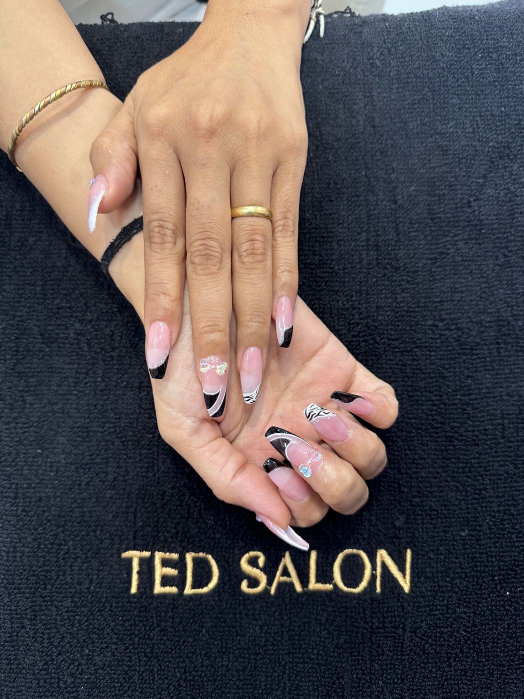 Long almond nail extensions in nude with black-and-white abstract art, on a Ted Salon towel.