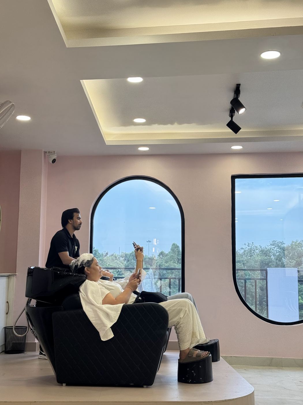 Guest relaxing at the hair-wash station beside arched windows on the 4th floor.